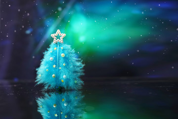 Wall Mural - Creative layout Concept for Christmas. Beautiful Christmas tree of feathers on aurora polaris background under snowfall. Colorful bright artistic image blue and green colors. Template for text.