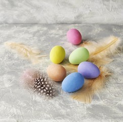 colored Easter eggs with feathers on a marble white table, selective focus