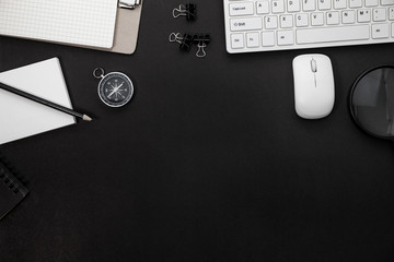 Wall Mural - Office desk table of Business workplace and business objects of keyboard,mouse,white paper,notebook,pencil,compass and magnifying glass on black background.