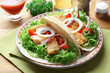 Plate with tasty fish tacos on table