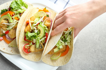 Sticker - Woman eating tasty fish tacos at table