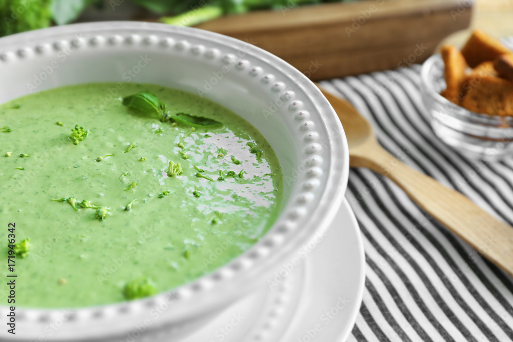 Plate with delicious broccoli cheese soup on table
