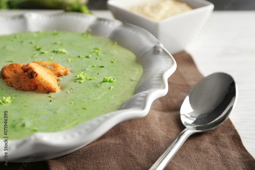 Plate with delicious broccoli cheese soup and croutons on table, closeup