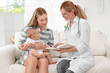 © Africa Studio - Doctor writing something in notebook and mother with baby at home