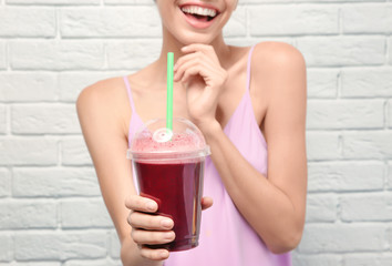 Poster - Beautiful young woman with fresh smoothie on white brick wall background