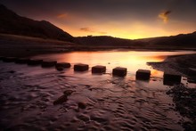 Sunrise Over The Stepping Stones That Allow Access To The Divided Beaches At Three Cliffs Bay On The Gower Peninsula In Swansea, South Wales, UK