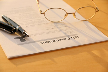 job description paper and pen,glasses on table