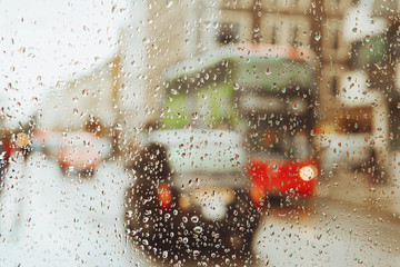 Raindrop on glass and red London bus lights