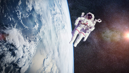 Wall Mural - astronaut in orbit of the planet Earth lit by the Sun