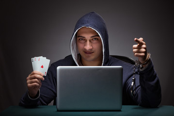 Wall Mural - Young man in handcuffs wearing a hoodie sitting in front of a la