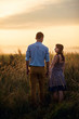 © gorynvd - Holding hands loving couple stands in the middle of the wheat field at sunrise or sunset