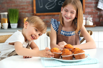 Canvas Print - Boy and girl eating yummy muffins in kitchen. Cooking classes concept