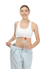 Poster - Beautiful young woman in oversized jeans with bottle of water on white background. Diet concept