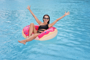 Poster - Beautiful young woman on inflatable donut in swimming pool