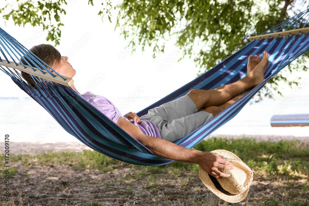 Young man relaxing in hammock outdoors