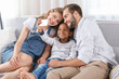 © Africa Studio - Happy couple with adopted African-American boy taking selfie while sitting on couch at home