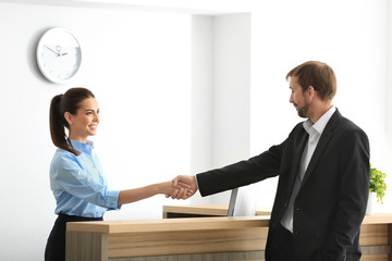 Wall Mural - Young female receptionist meeting client in office