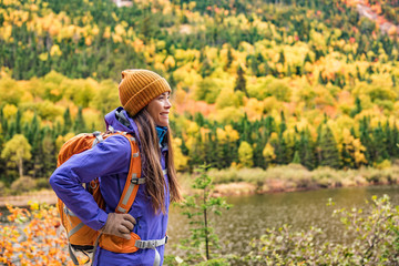 Wall Mural - Autumn hiker girl outdoor in nature forest lake backpacking for camping travel trip. Happy Asian woman hiking outdoors with bag and hat, cold outerwear gear.