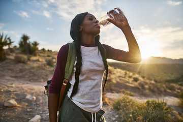 Wall Mural - african american woman taking a break to drink from water bottle while hiking at red rock canyon nev