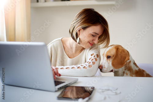 Poster Caucasian businesswoman playing with dog in home office