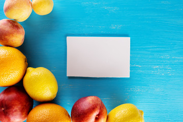 Wall Mural - Fresh tropical fruits on blue background with sheet for notes