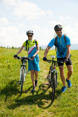 Wall Mural - ACTIVE Young couple biking on a forest road in mountain on a spring day