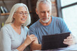 Delighted retired couple using tablet at home