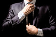 Businessman adjusting his suit on black background