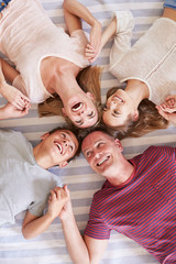 Wall Mural - Overhead View Of Family With Teenage Children Lying On Bed