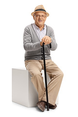 Poster - Mature man with a cane sitting on a cube