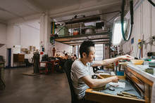 Male Jeweller Working At Jewellery Workshop Workbench