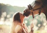 Fototapeta Konie - Woman kissing her horse at sunset, outdoors scene