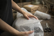 © Mint Images - A woman wrapping an item in bubble wrap, a parcel being prepared for despatch.