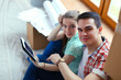 © lenets_tan - Couple moving in house sitting on the floor with ipad. Couple