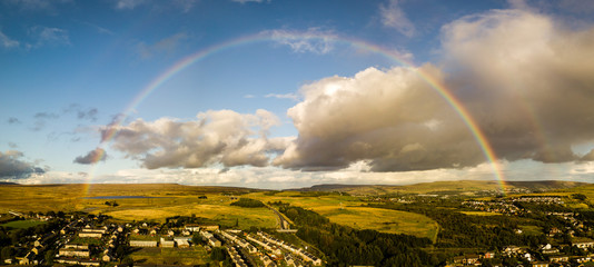 Wall Mural - a full rainbow viewed from the air over a small rural town