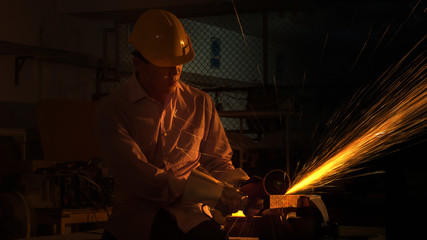 the man worker uses grinding cutting machine to cut metal, focus on flash light line of sharp spark,