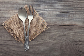 Wall Mural - Old fork and spoon on a wooden table napkin and burlap, grunge rustic style, top view.