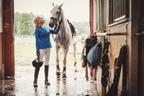 Photographie Middle-aged woman with her horse in a stall