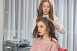 © DenisProduction.com - Young female at the hairdresser. Stylist with hair straightener.
