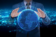 businessman in blue suite holding virtual globe with night city background