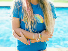 Blonde Girl In Rainbow Tee With Lots Of Colorful Indie Bracelets On Wrist
