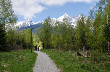 Two hikers walk up the alley with distant alpine peaks in the background