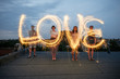 © VegterFoto/Stocksy - Four people writing the word 'love' with sparklers.