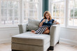 © Jakob/Stocksy - Beautiful woman sitting in a big chair reading a magazine and drinking coffee