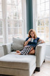 © Jakob/Stocksy - Beautiful woman sitting in a big chair reading a magazine and drinking coffee