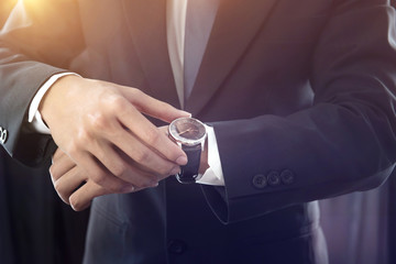 closeup watch on hand businessman, he checking time on watch, dark tone.