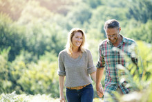 Happy Mature Couple Walking In Countryside On Sunny Day