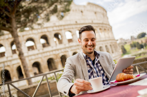 Plakat Młody człowiek siedzi i ma filiżankę kawy w Rzym, Włochy