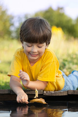 Wall Mural - boy play with autumn leaf ship in water, chidren in park play with leaf in river