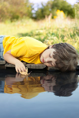 Wall Mural - boy play with autumn leaf ship in water, chidren in park play with leaf in river